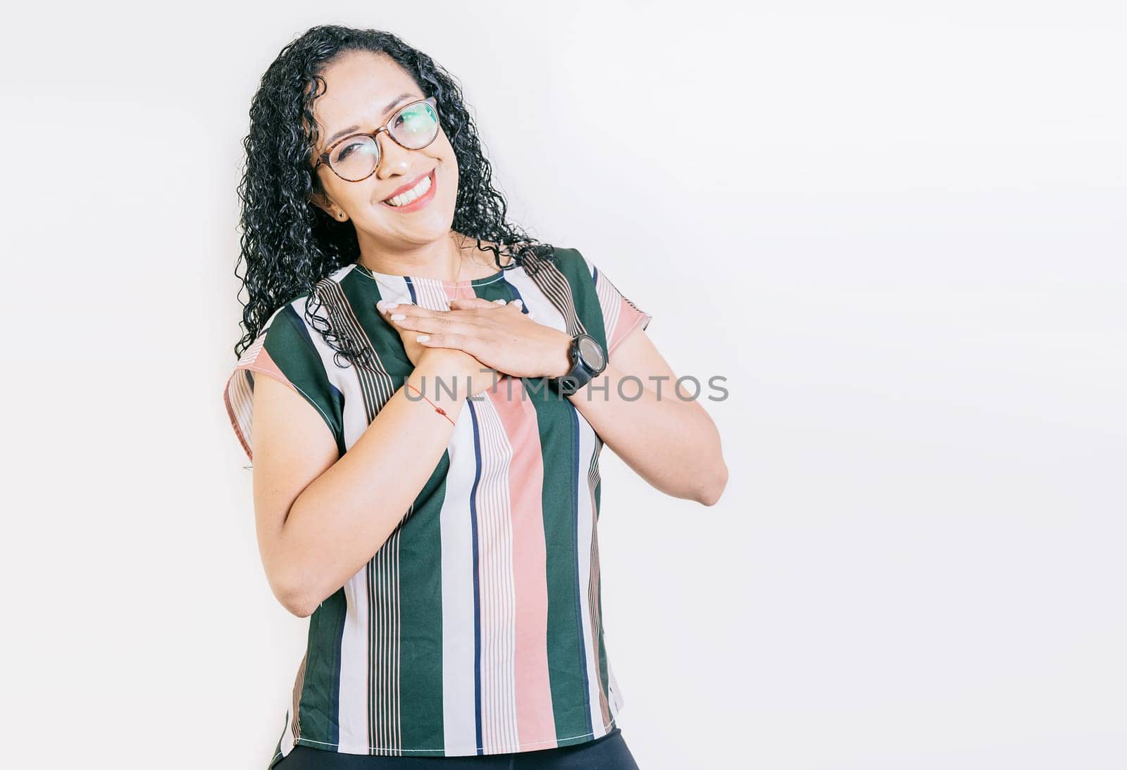 Grateful young woman smiling with hands on chest isolated. Positive smiling girl with hands on chest. Grateful people with hands on chest by isaiphoto