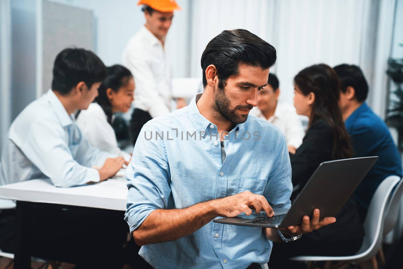 Engineer team leader portrait with diverse group of civil engineer and client working together on architectural project, reviewing construction plan and building blueprint at meeting table. Prudent