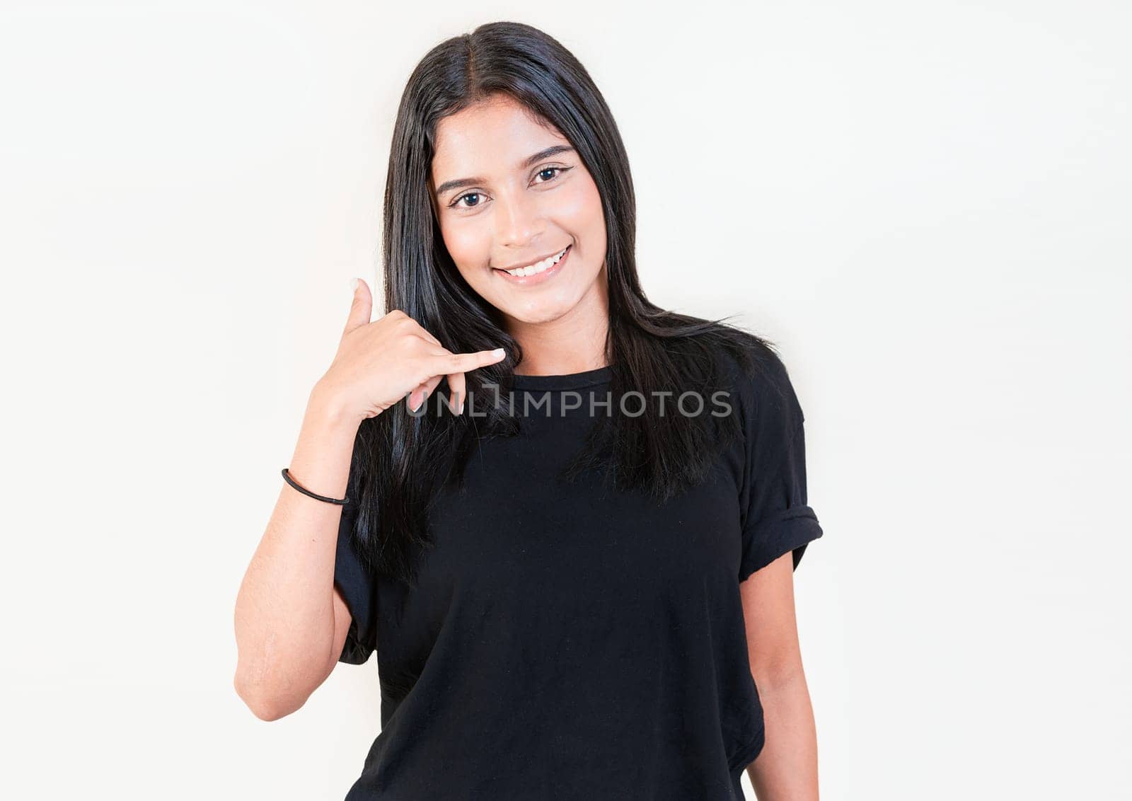 Smiling young girl gesturing call me with hand isolated. Happy latin girl gesturing call with fingers isolated