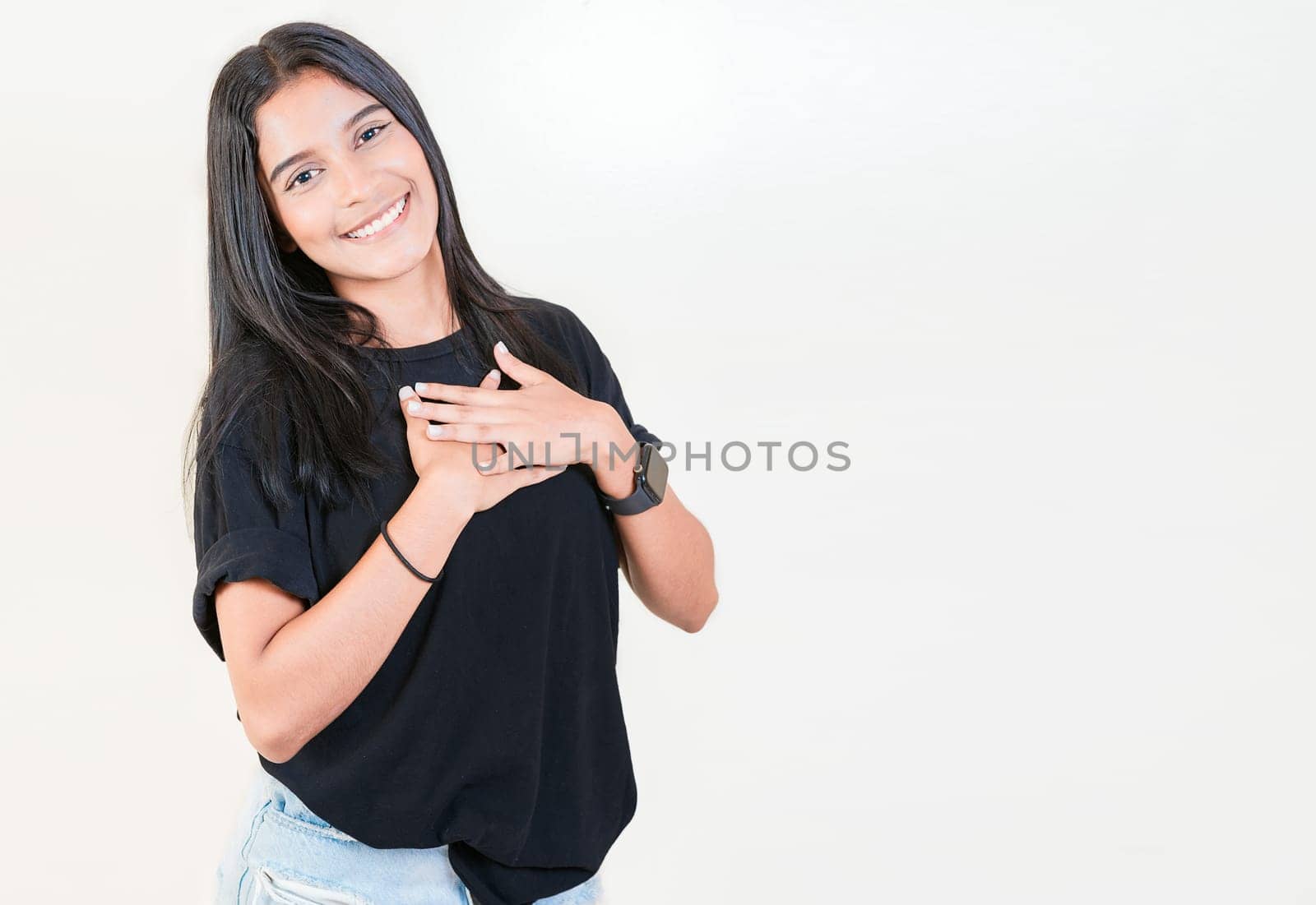 Grateful teenage girl smiling with hands on chest isolated. Positive latin girl with hands on chest. Thankful people with hands on heart by isaiphoto