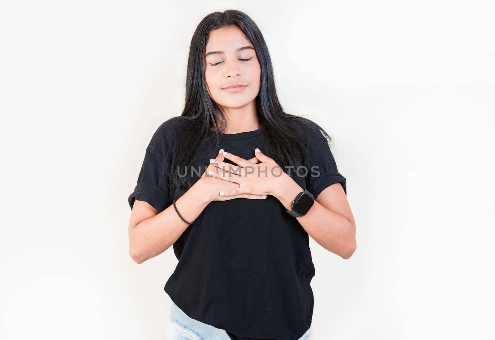 Thankful people with hands on chest. Grateful teenage girl smiling with hands on chest isolated. Positive latin girl with hands on chest by isaiphoto