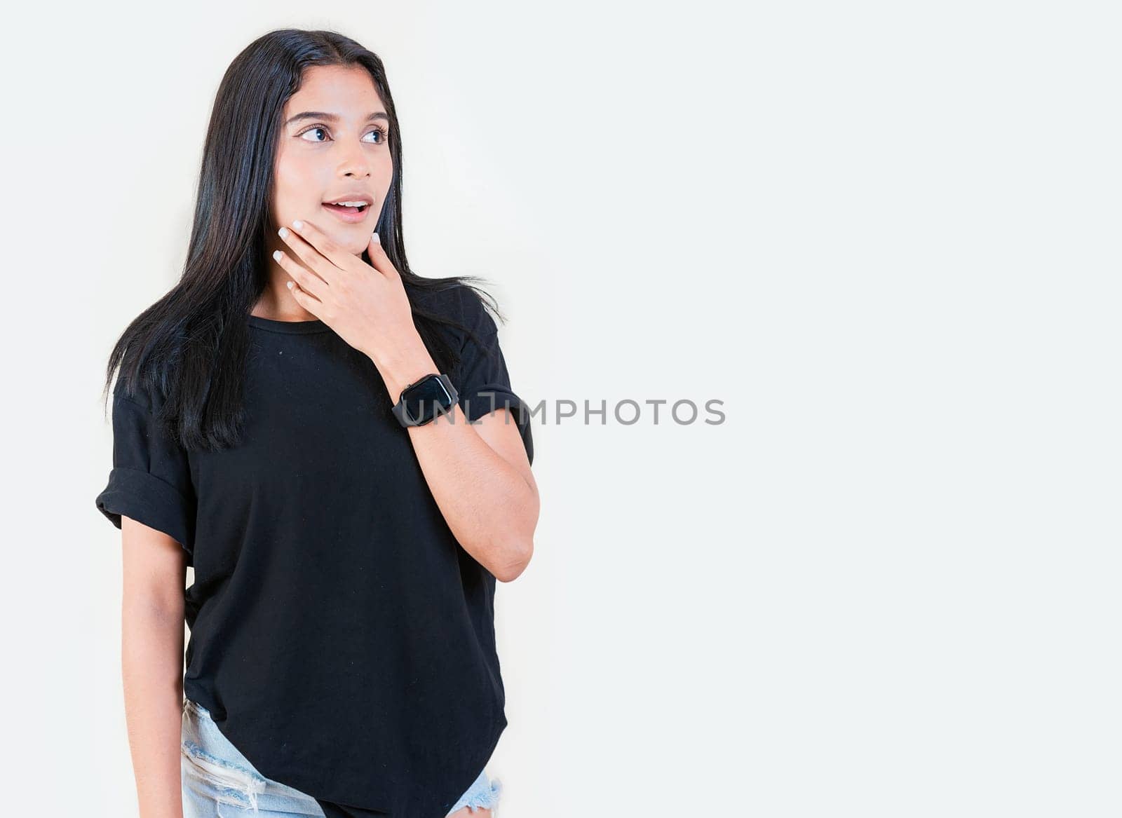 Surprised teen girl looking at an advertisement to side. Surprised Latin girl looking at a promotion to the side. Amazed people with hand on chin looking at blank space by isaiphoto