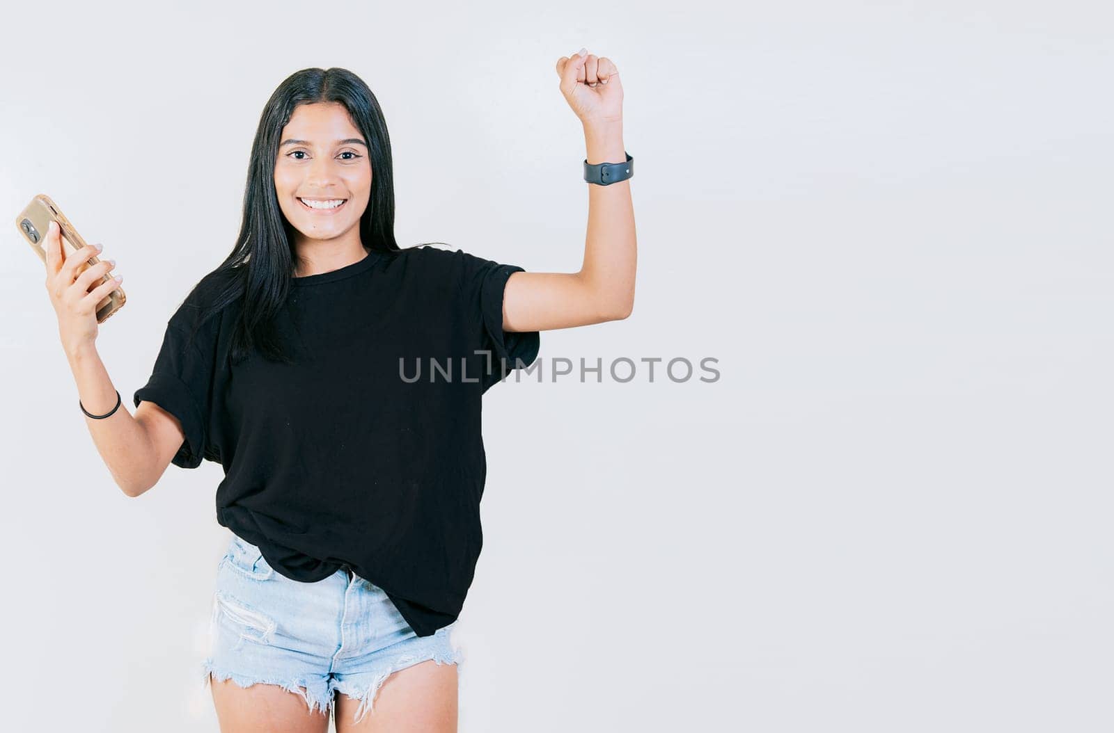 Happy teen girl celebrating with phone isolated. Happy people holding smartphone and celebrating. Winner happy young girl holding cell phone by isaiphoto