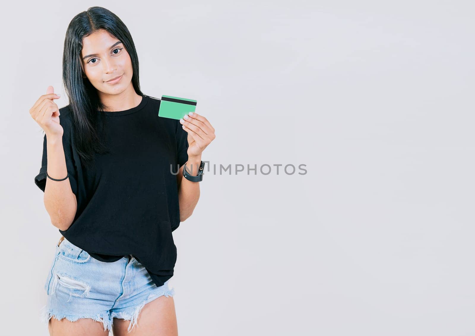 Girl holding credit card making money gesture with fingers isolated, looking at camera by isaiphoto