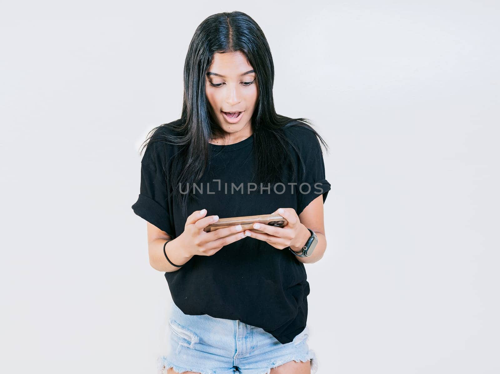 Happy teen girl using and looking phone isolated. Cheerful young girl looking at a promotion on the phone isolated by isaiphoto