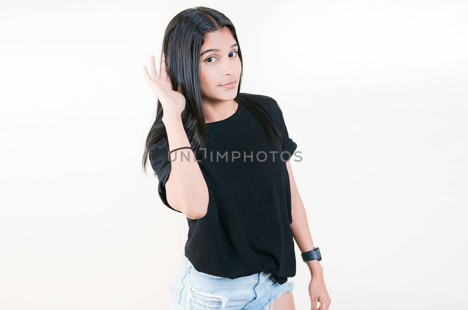 Young girl with hand on ear hearing a rumor isolated. Beautiful teenage girl listening to a rumor isolated by isaiphoto