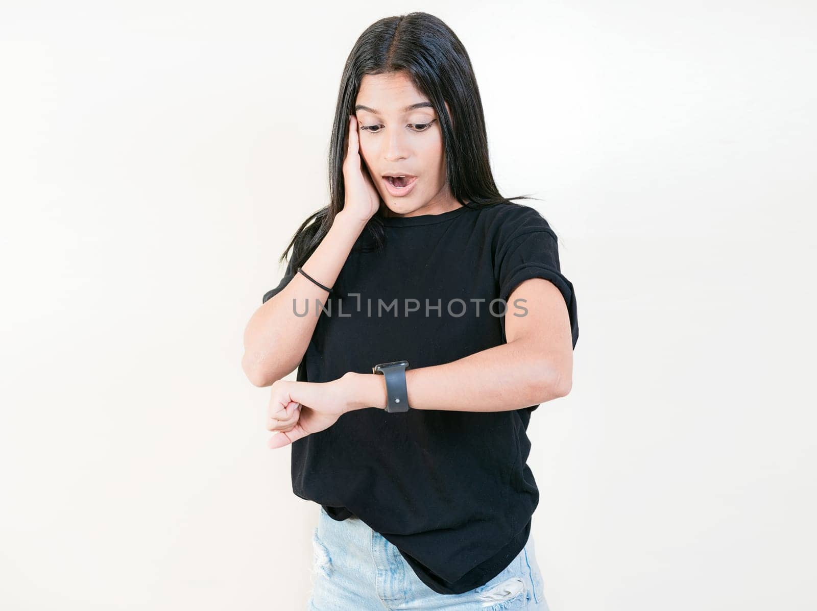 Surprised young woman looking at wrist watch. Worried young woman looking at her watch isolated by isaiphoto