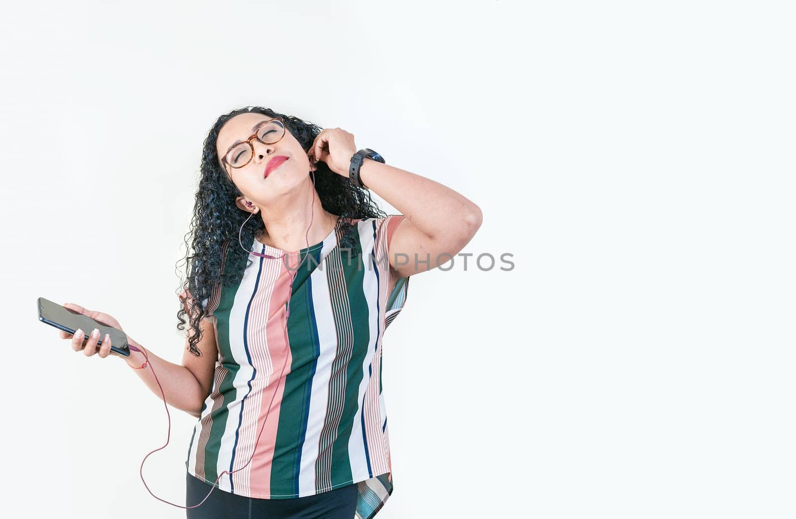 Relaxed afro girl enjoying music with phone isolated. Young afro woman listening to music with earphones isolated by isaiphoto