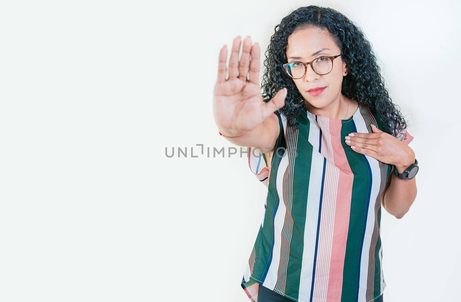 Young afro woman rejecting with the palm hand isolated. Afro girl gesturing stop isolated. Latin girl gesturing stop with palm hand isolated by isaiphoto