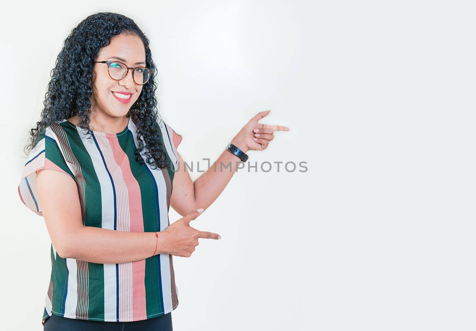 Happy young afro woman pointing a promotion at side. Cheerful afro girl pointing an offer isolated. Beautiful latin girl pointing to a banner to the side by isaiphoto