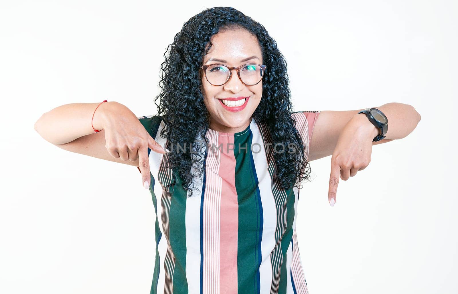 Happy afro young woman pointing at advertising down isolated. Smiling latin woman pointing and looking down by isaiphoto