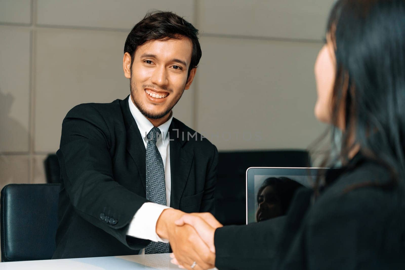 Business people agreement concept. Businessman and Asian businesswoman do handshake in the office. uds