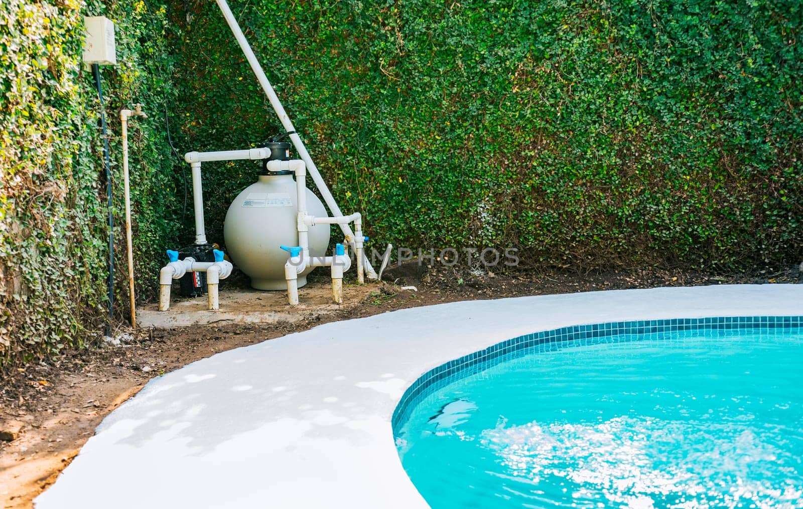 Pool pump with sand filter installed near of swimming pool. Home swimming pool filter and treatment plant installed. Pool purification and maintenance system by isaiphoto