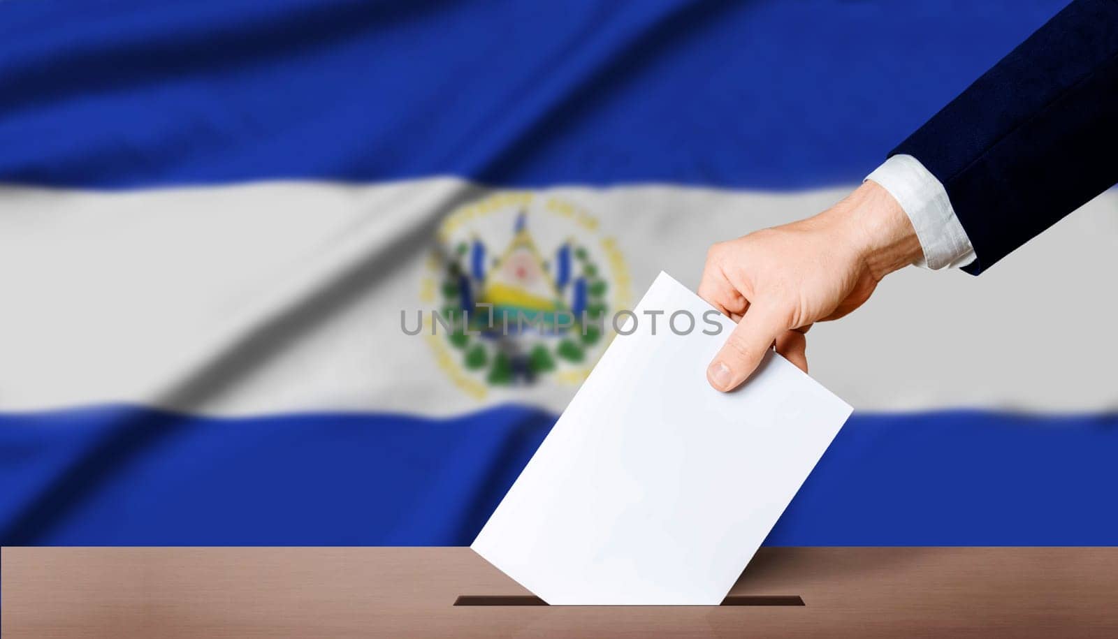 Hand holding ballot in voting ballot box with El Salvador flag in background. El Salvador presidential elections concept