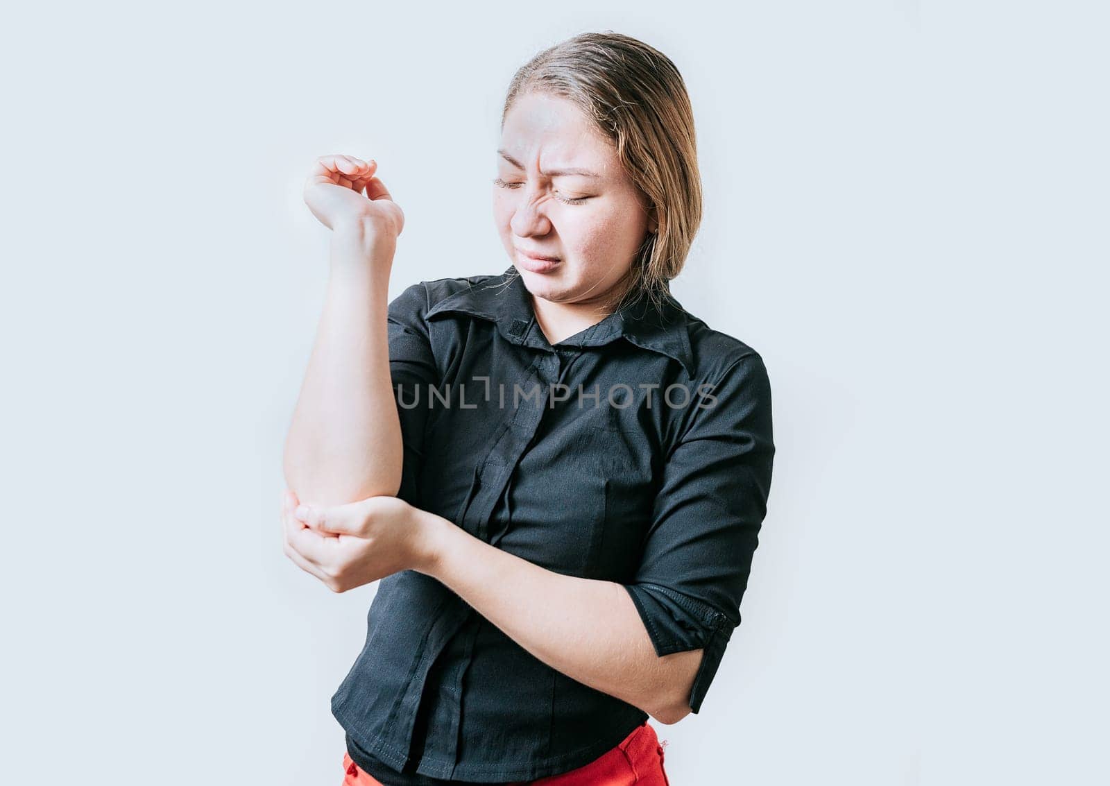 Young woman with elbow pain isolated. Woman with pain rubbing her elbow isolated. Arthritis and rheumatism concept by isaiphoto