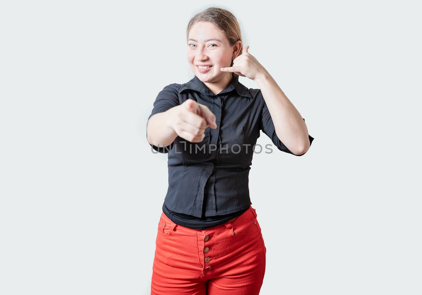 Smiling Beautiful woman gesturing call me and pointing at camera. Friendly girl gesturing call me with fingers isolated