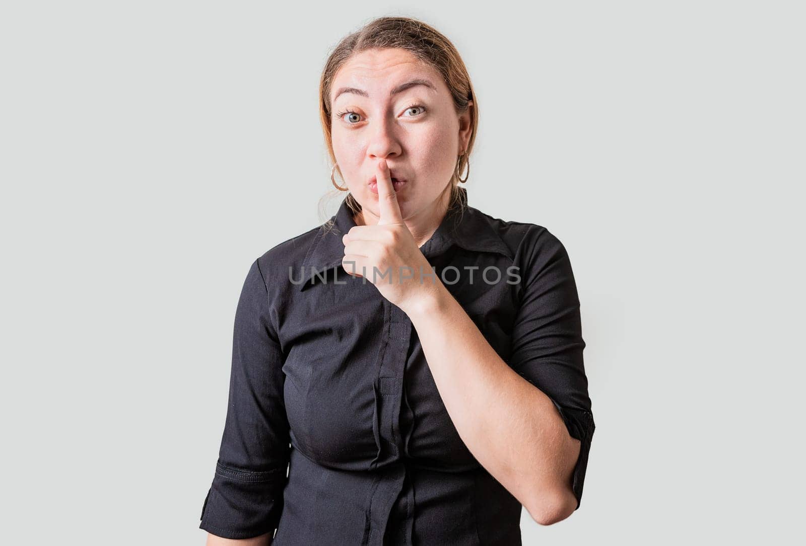 Amazed woman making silence gesture with finger. Blonde girl making silence gesture isolated by isaiphoto