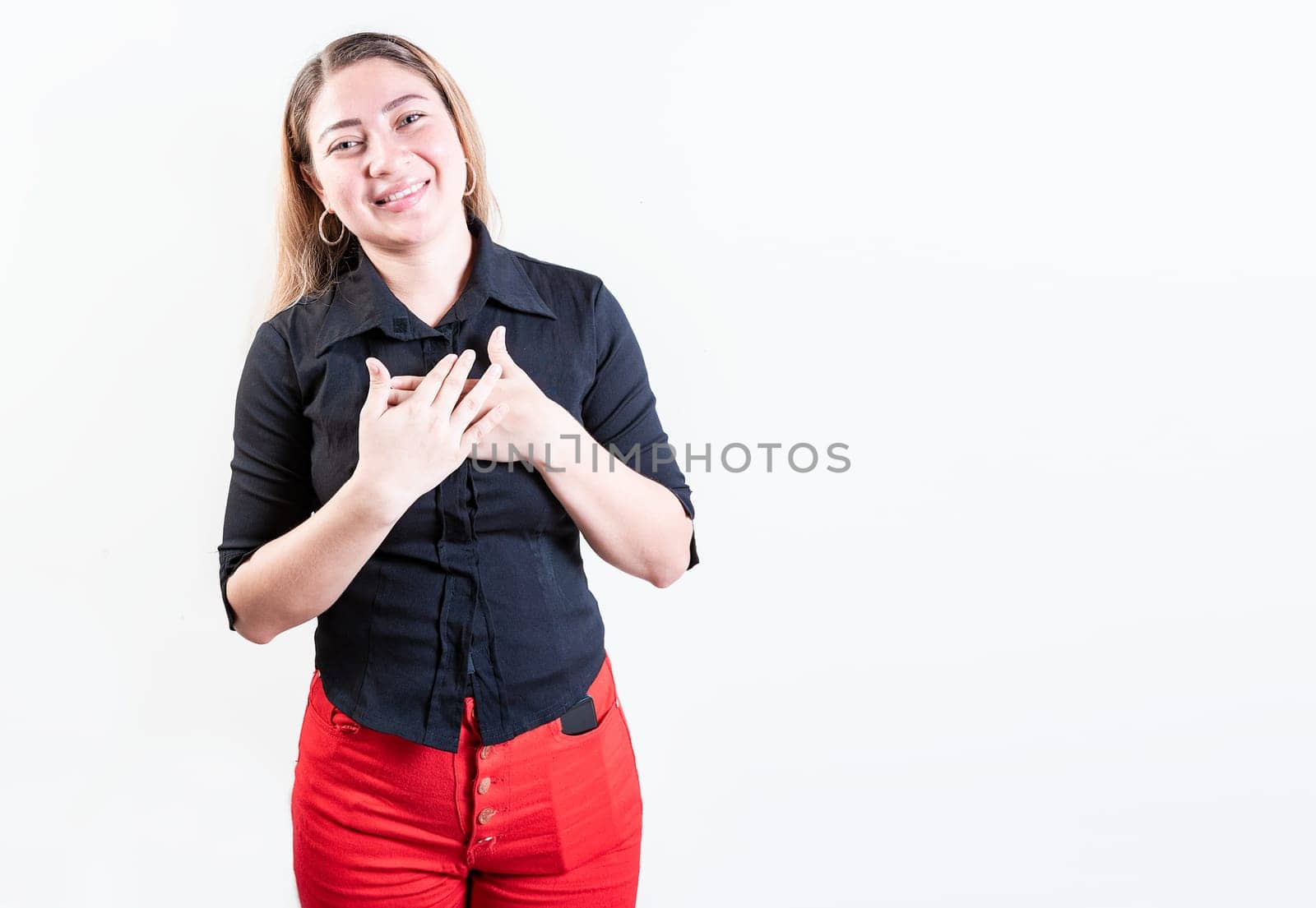 Thankful young woman with hands on chest. Grateful teenage girl smiling with hands on chest isolated. Positive latin girl with hands on chest by isaiphoto