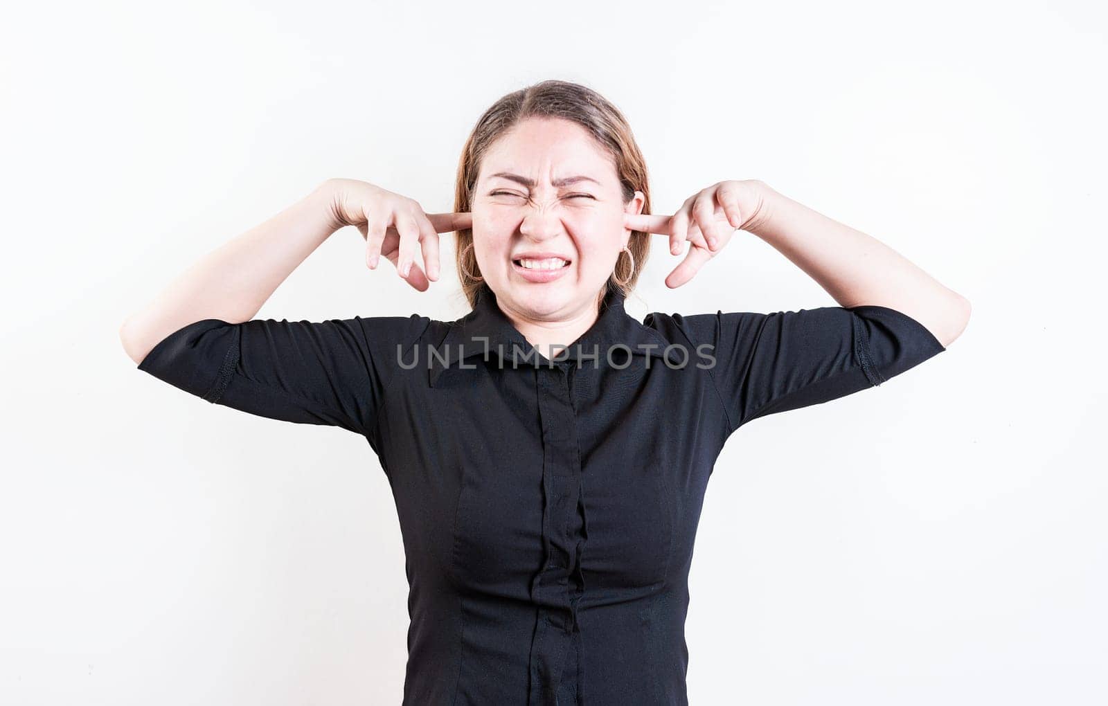 Displeased young woman covering her ears isolated. Latin girl covering her ears tightly isolated by isaiphoto