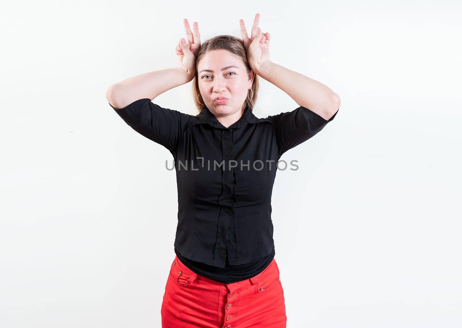 People making horns gesture with their fingers, gesture of betrayal. Young woman making horns gesture with fingers. Infidelity concept by isaiphoto