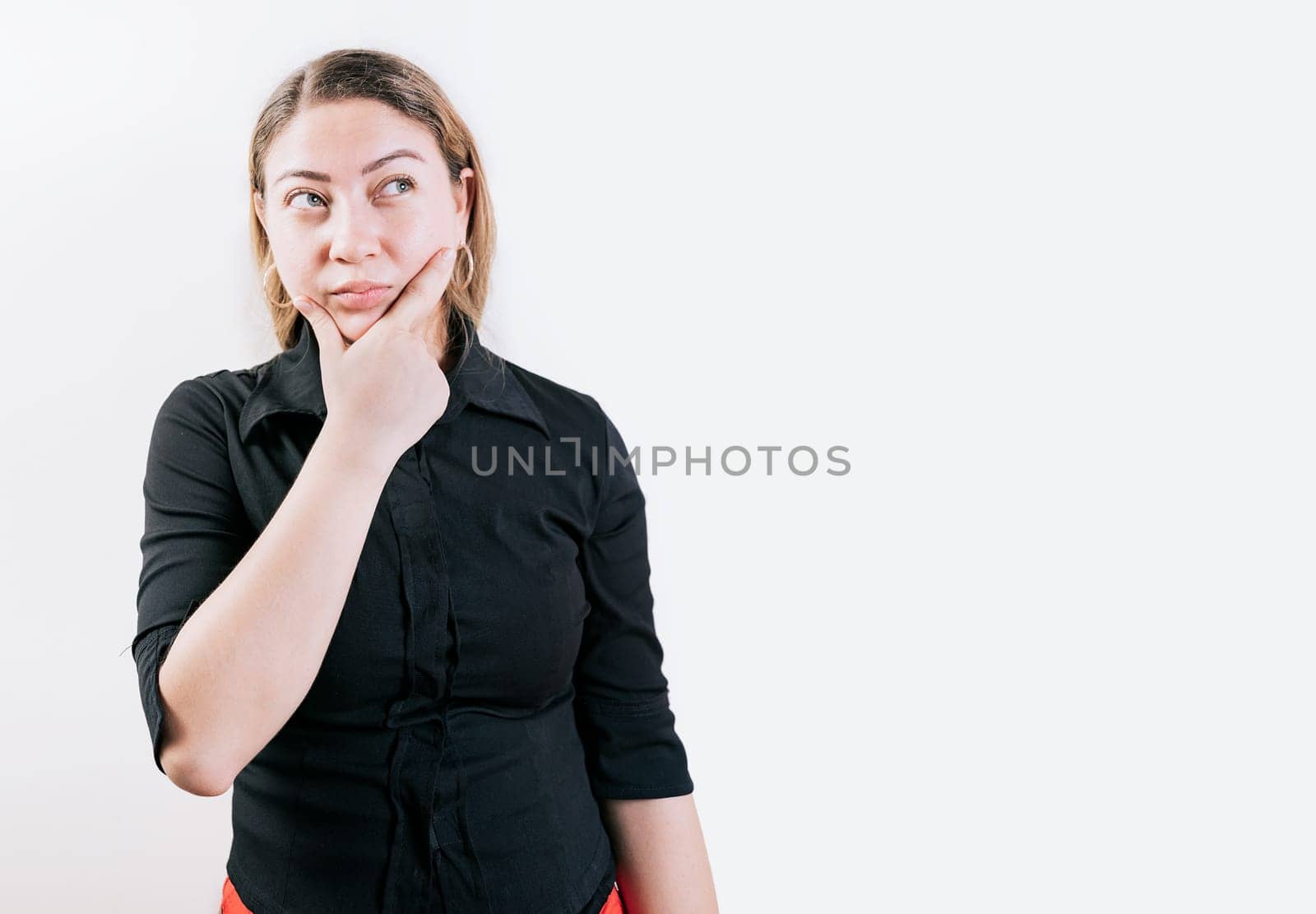 Thoughtful and confused girl with hand on chin isolated. Pensive young woman with hand on chin isolated