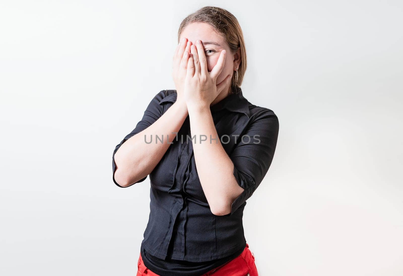 Embarrassed girl covering her face and looking at the camera. Shy girl covering her face and looking at the camera isolated