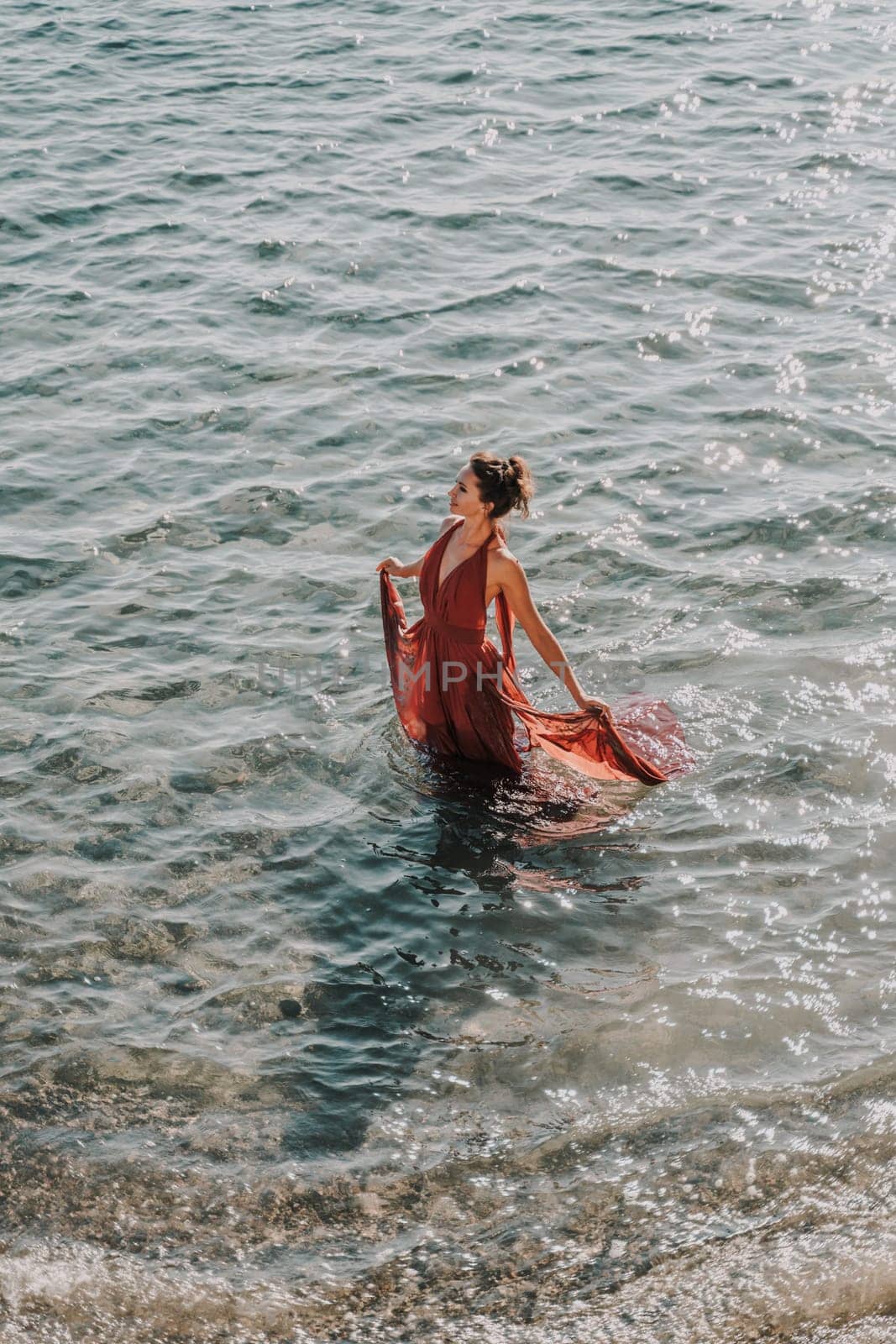 Woman red dress sea. Female dancer in a long red dress posing on a beach with rocks on sunny day by Matiunina