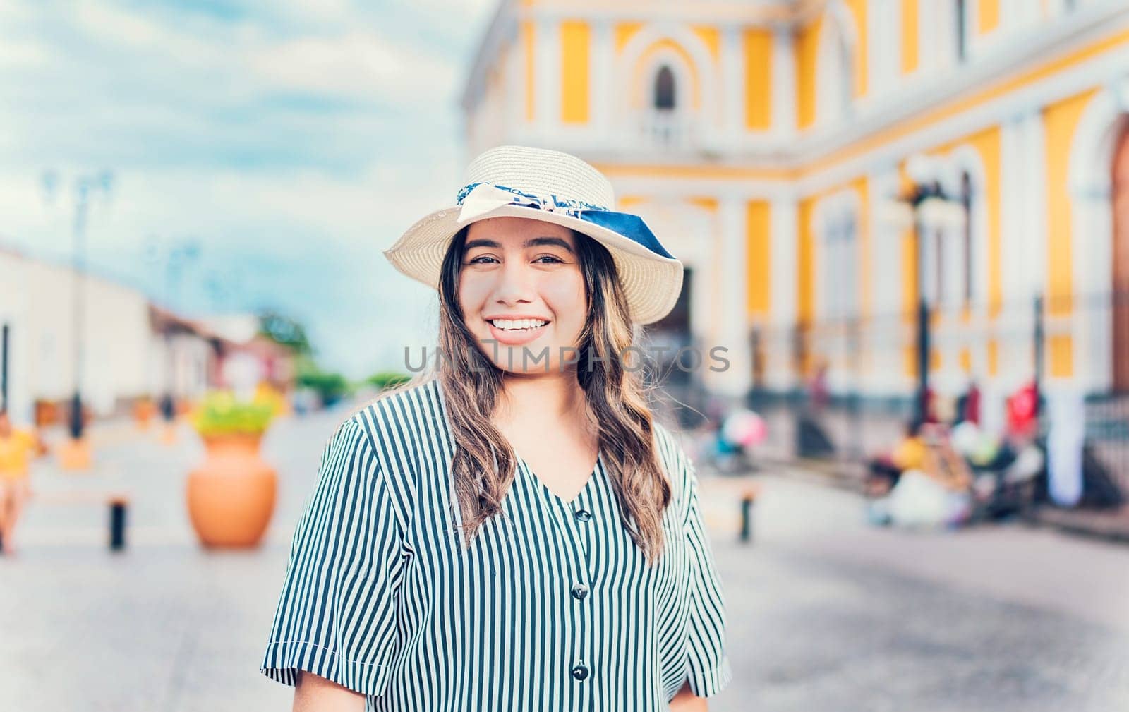 Lifestyle of happy traveler woman in a tourist square. Portrait of smiling tourist girl on the streets of Granada, Nicaragua by isaiphoto