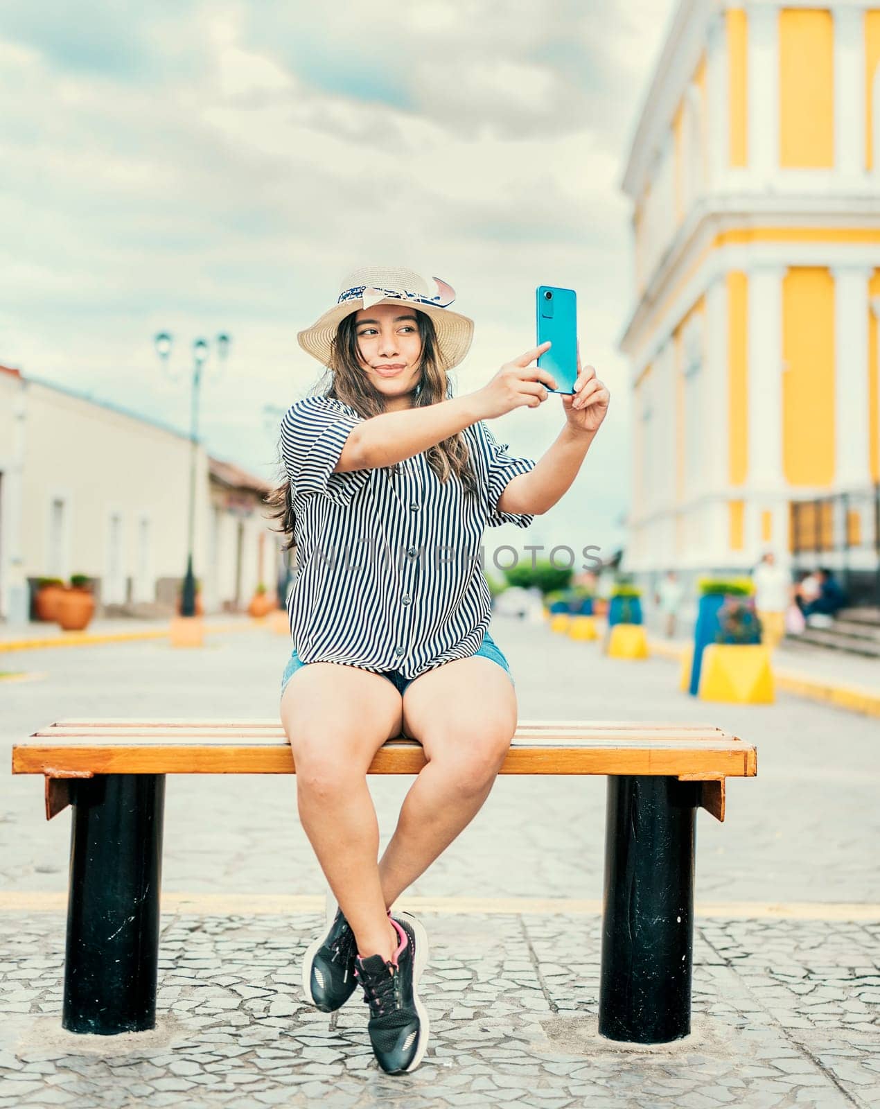 Lifestyle of tourist girl sitting taking selfie in the cathedral of Granada. Young travel woman sitting taking a selfie outdoors