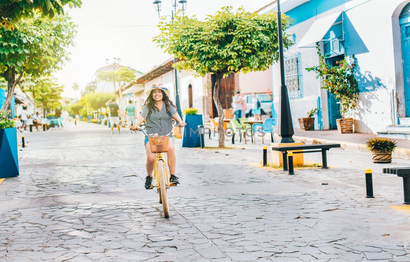 Young tourist woman riding a bicycle on the streets of Granada, Nicaragua. Happy tourist girl riding a bicycle on Calzada street