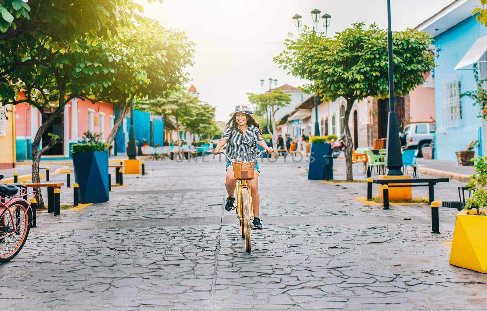 Happy tourist girl riding a bicycle on Calzada street. Young tourist woman riding a bicycle on the streets of Granada, Nicaragua by isaiphoto