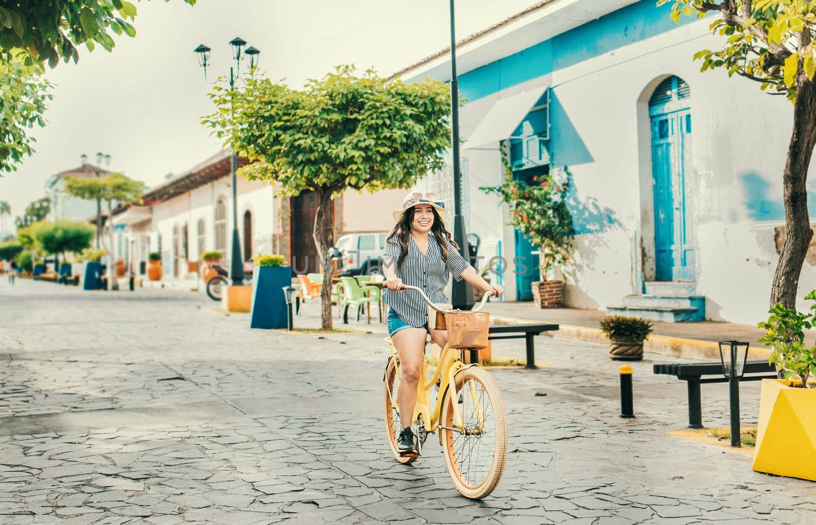 Beautiful and happy girl riding a bicycle on the street of La Calzada, Granada, Nicaragua. Tourist woman riding a bicycle on the streets of Granada