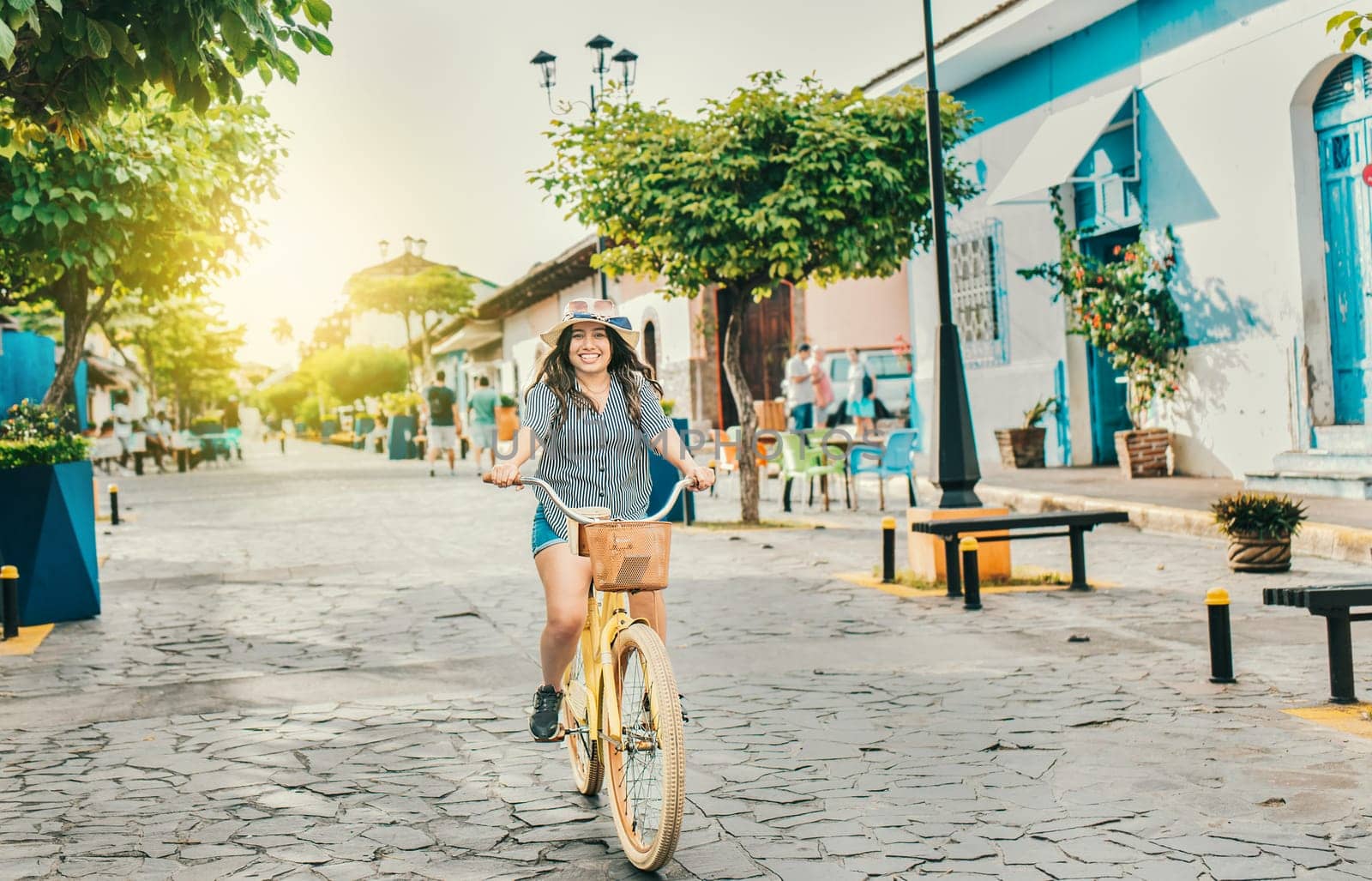 Smiling tourist woman riding a bicycle on the streets of Granada. Beautiful girl riding a bicycle on the street of La Calzada, Granada, Nicaragua by isaiphoto