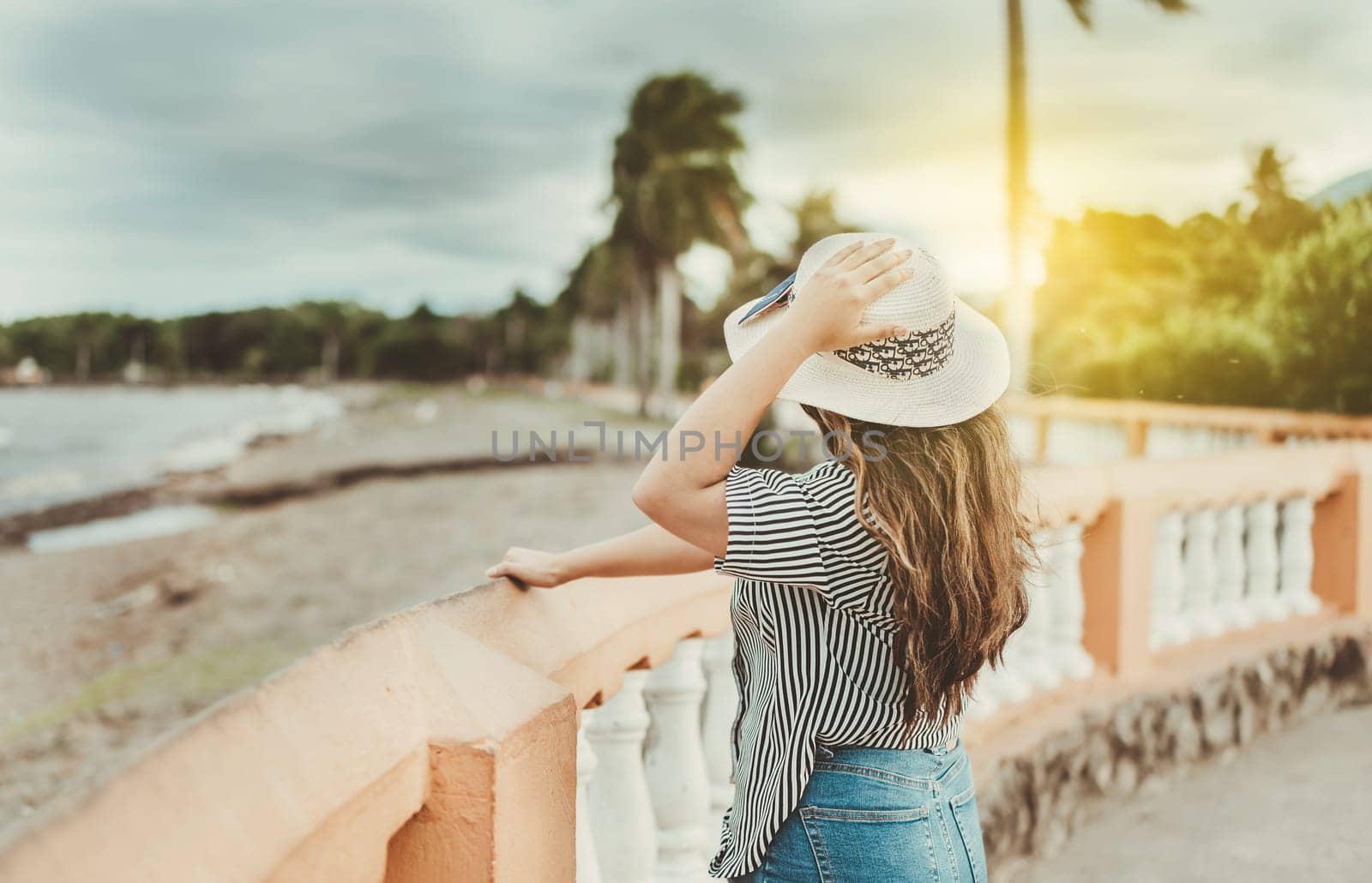 Beautiful girl on a pier holding her hat. Tourist woman near a port holding her hat by isaiphoto
