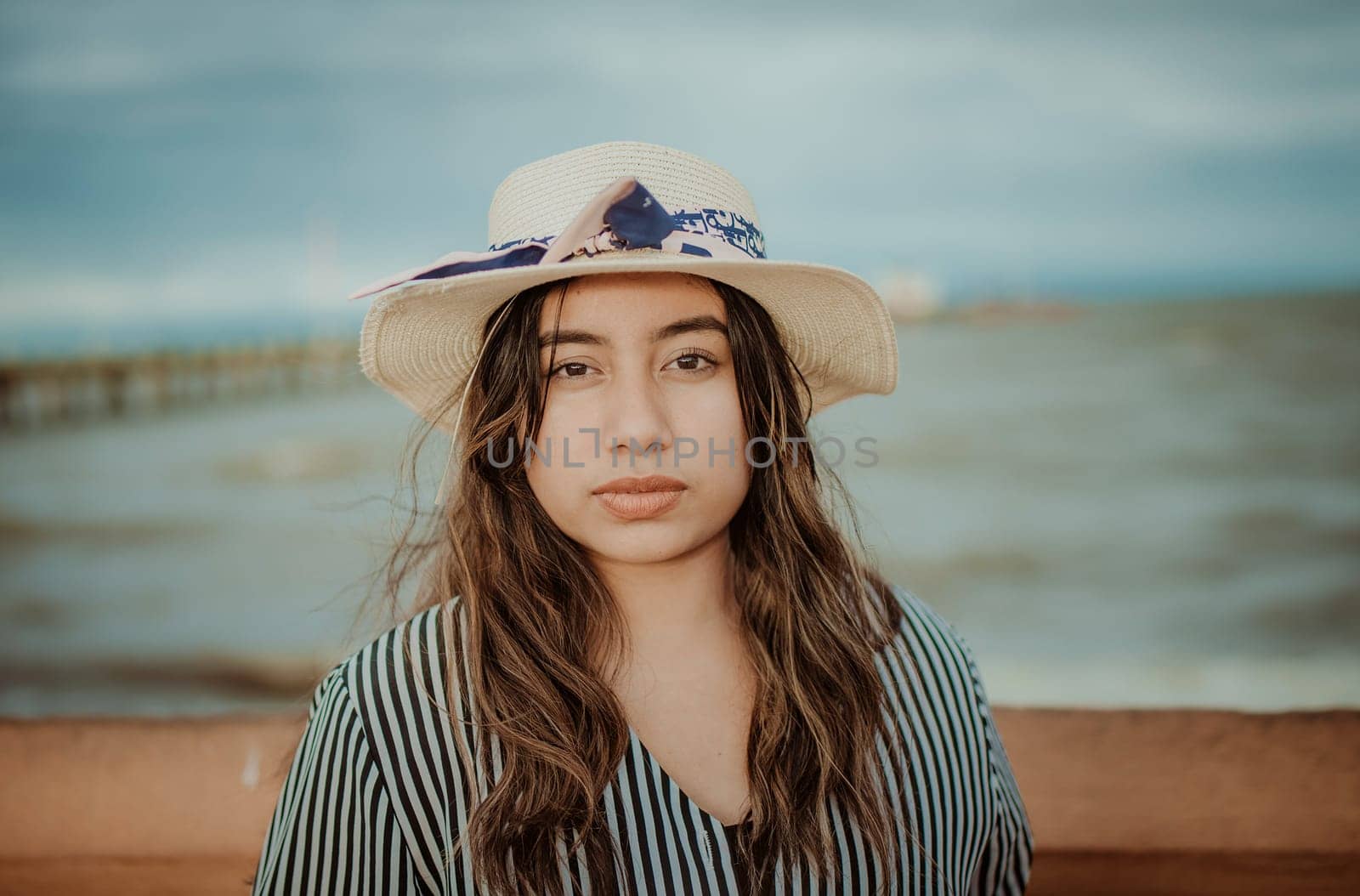 Portrait of beautiful latin girl in hat on the pier. Portrait of young tourist woman in hat on a pier by isaiphoto