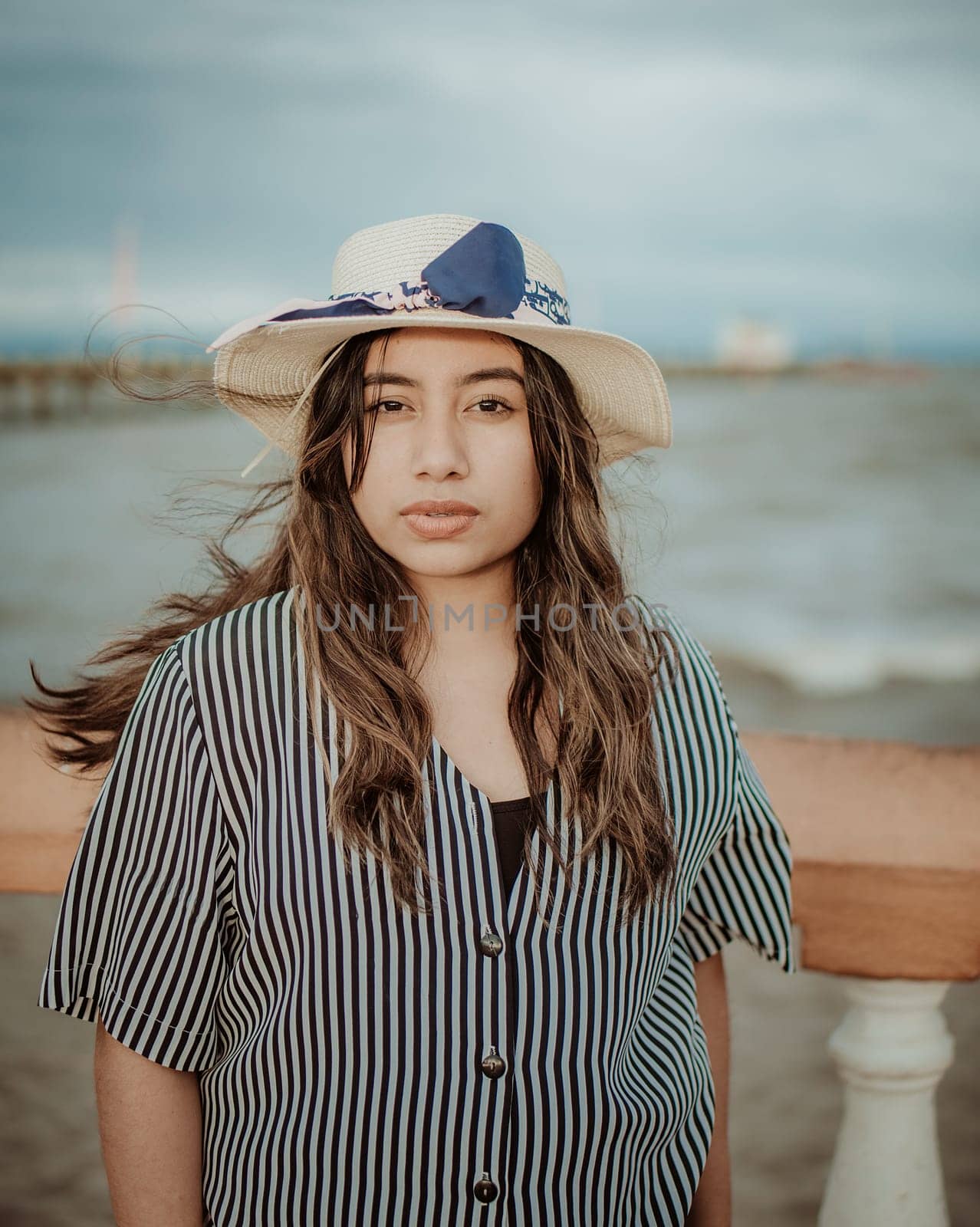 Portrait of attractive woman in hat on the pier looking at camera. Portrait of young tourist woman in hat on a pier by isaiphoto
