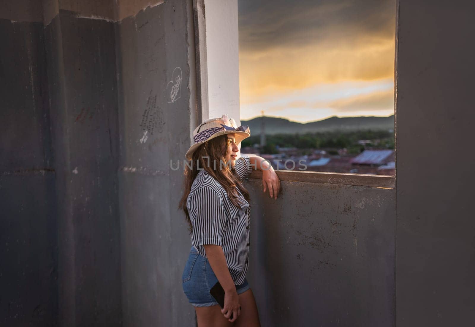 Young woman tourist looking at the sunset through an old window in Granada, Nicaragua