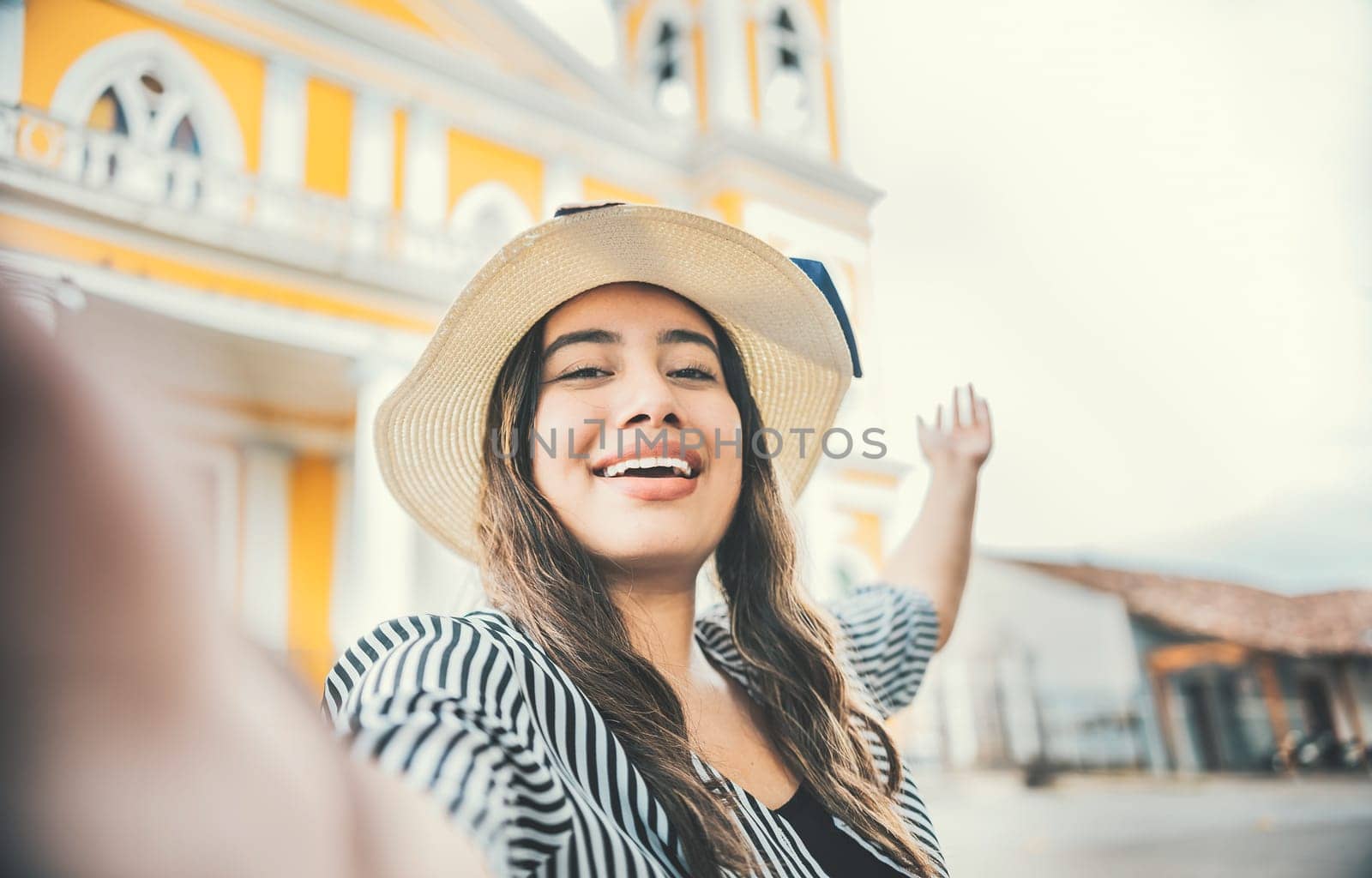 Lifestyle of tourist girl in hat taking a selfie in a square. Granada, Nicaragua. Smiling tourist girl in hat taking a selfie in a square by isaiphoto