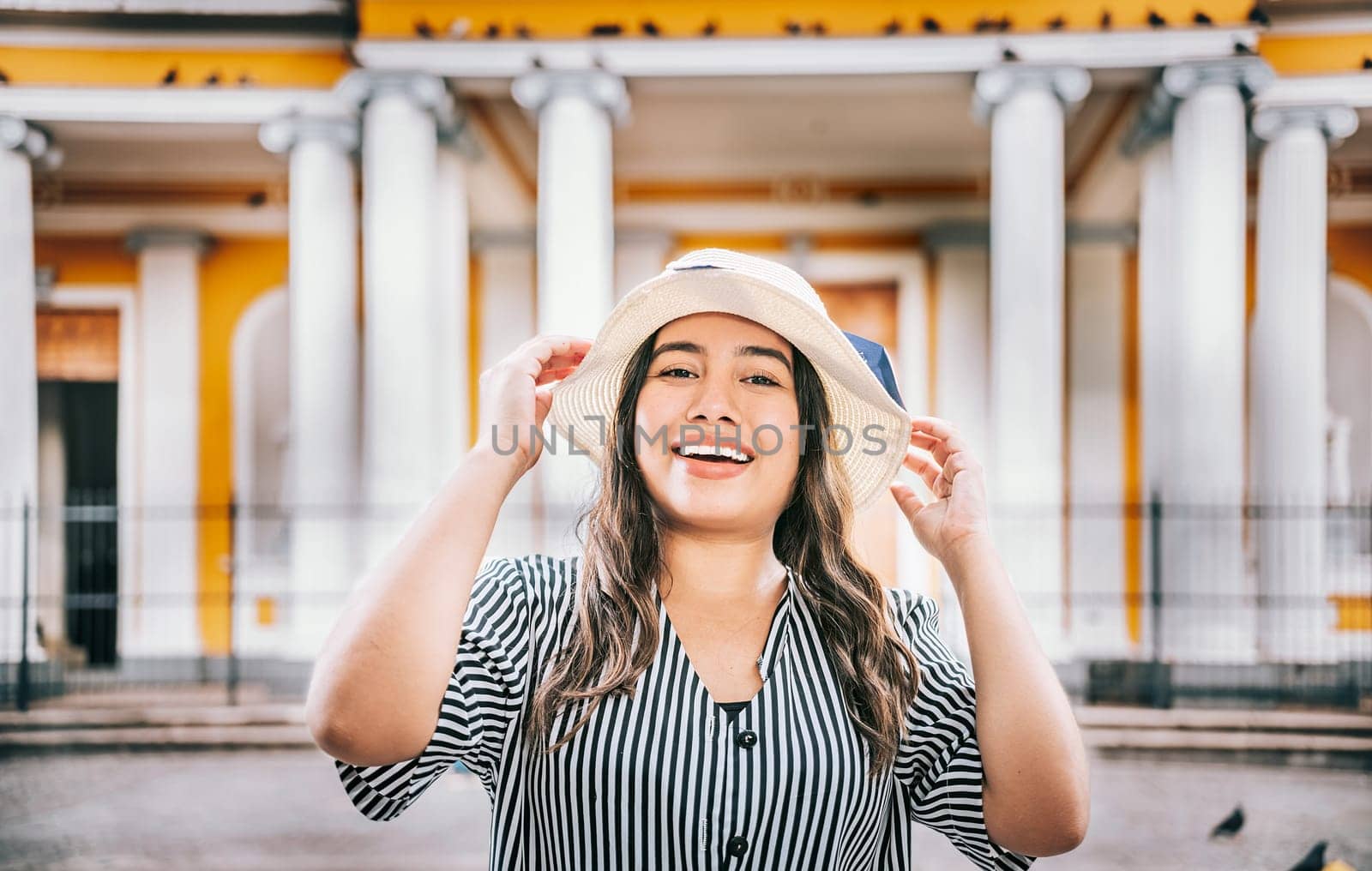 Portrait of a tourist girl with hat in a tourist square. Granada, Nicaragua. Portrait of smiling woman traveler in a tourist square by isaiphoto