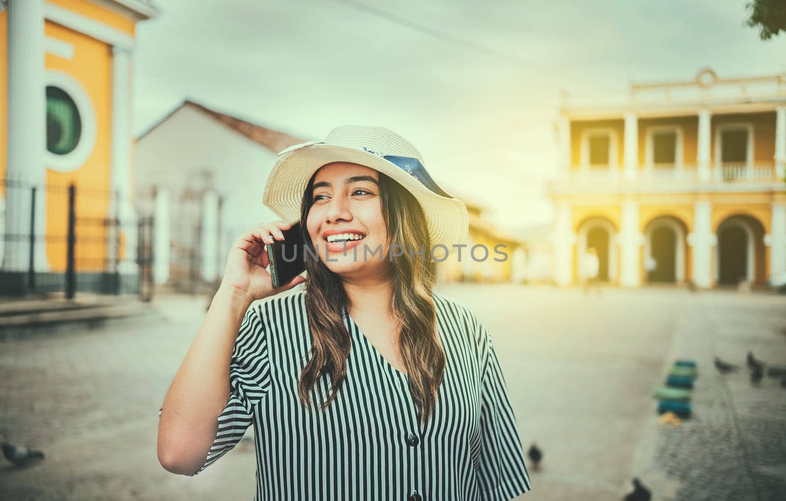 Beautiful tourist girl talking on cell phone in the square. Granada, Nicaragua. Happy travel woman calling on the phone in a tourist plaza