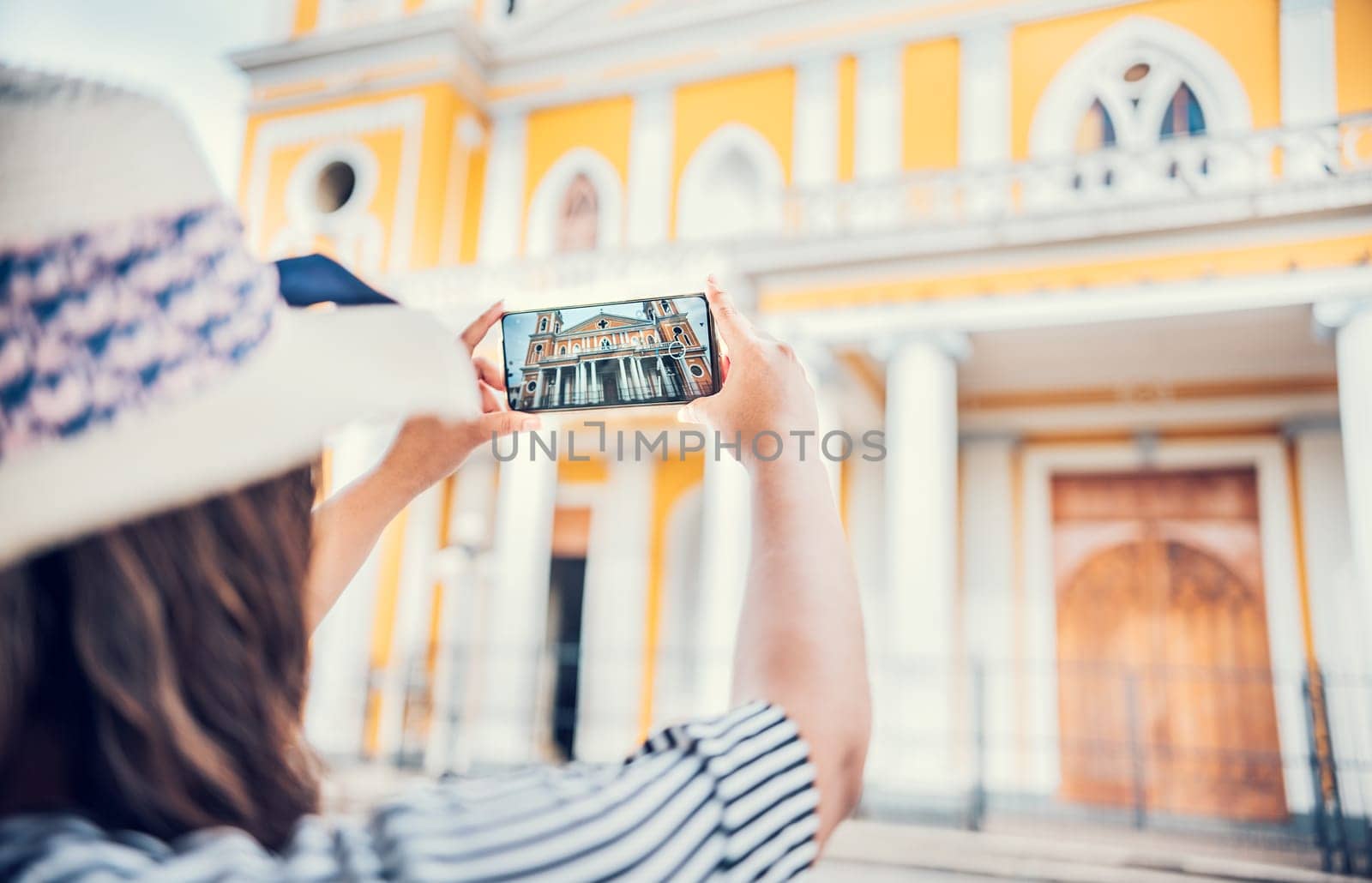 Tourist girl taking photos of the Granada cathedral with mobile phone. Hands of tourist woman taking photos with cell phone by isaiphoto