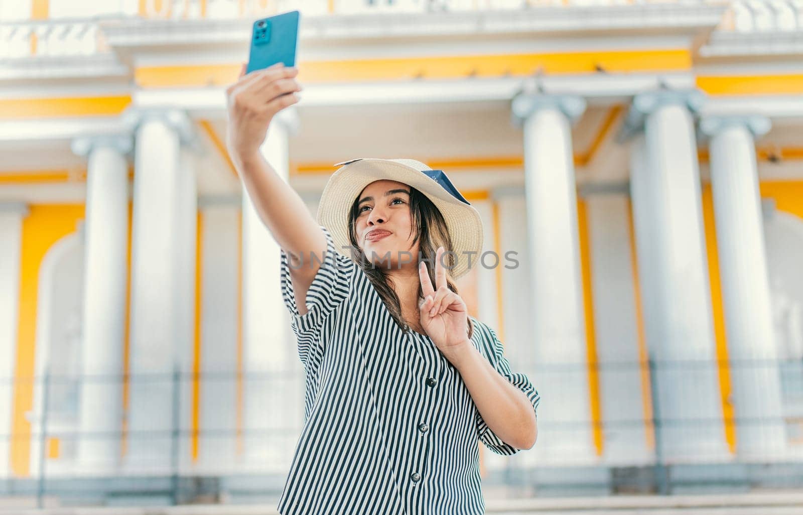 Beautiful tourist girl taking selfie in the cathedral of Granada. Young tourist woman with hat taking selfie in a square. Selfies and vacation concept by isaiphoto