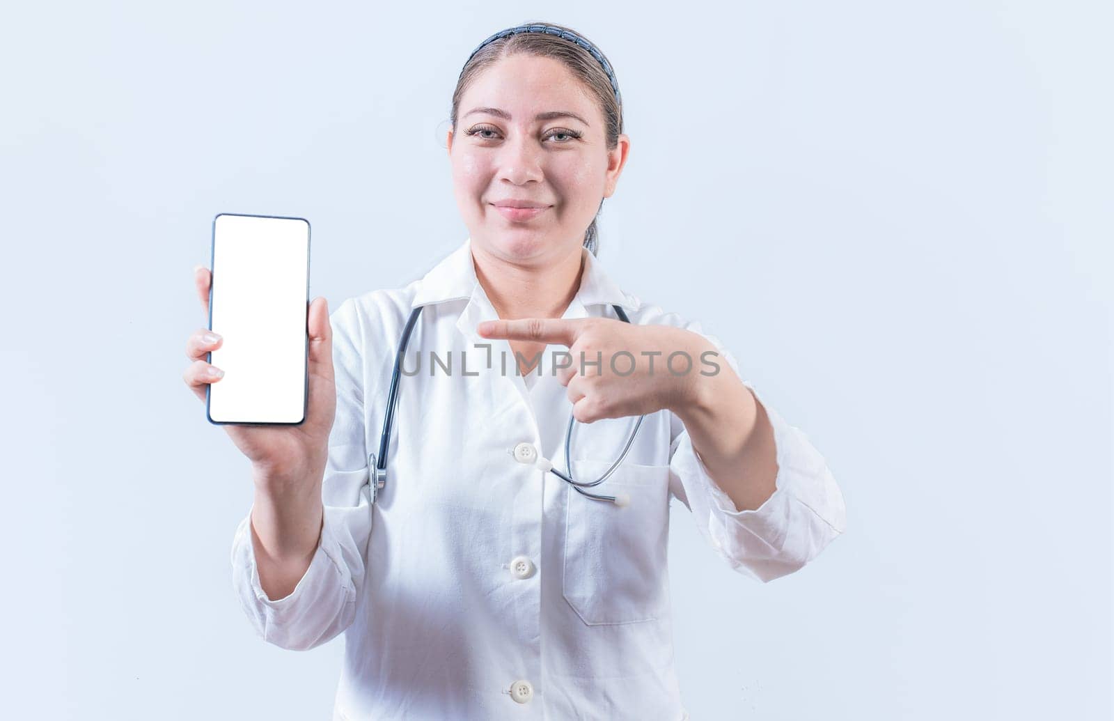 Beautiful female doctor holding and pointing at phone screen. Young female doctor showing and pointing at smatphone screen isolated by isaiphoto