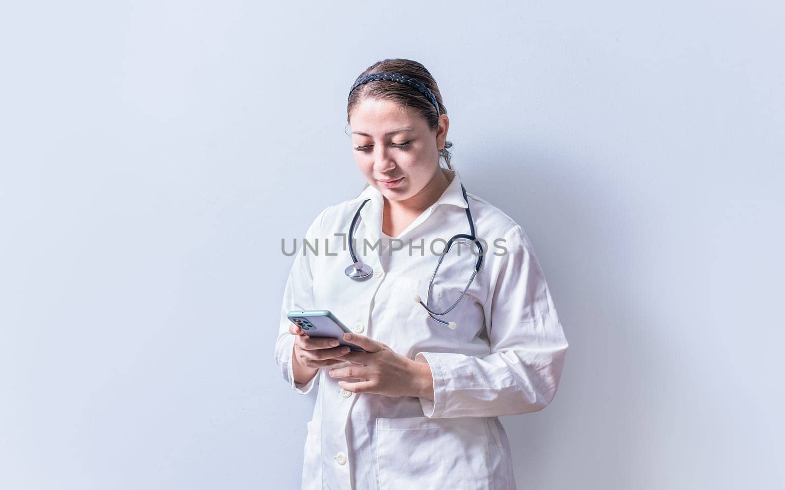 Young female doctor with telephone isolated. Smiling female doctor using phone on isolated background by isaiphoto
