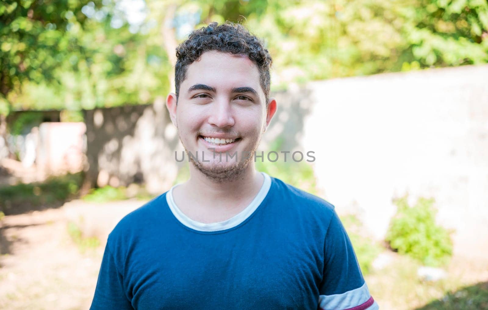 Portrait of Latin American man looking and smiling at the camera. Portrait of cheerful young latin guy smiling at camera outdoors