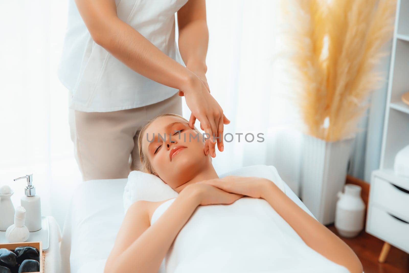 Caucasian woman enjoying relaxing anti-stress head massage and pampering facial beauty skin recreation leisure in dayspa modern light ambient at luxury resort or hotel spa salon. Quiescent