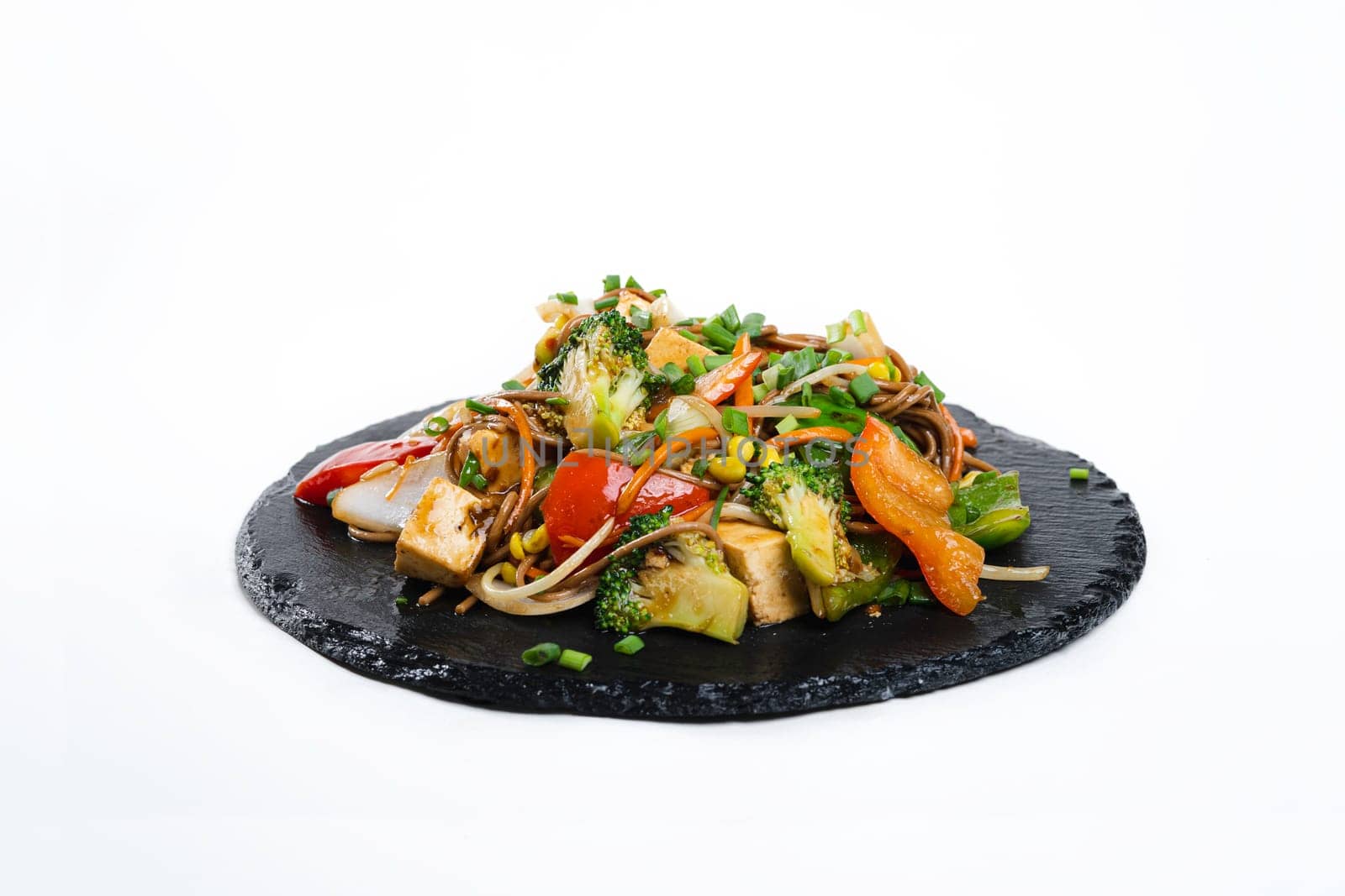 fried assorted vegetables with meat in a flat plate on a white background, side view by tewolf