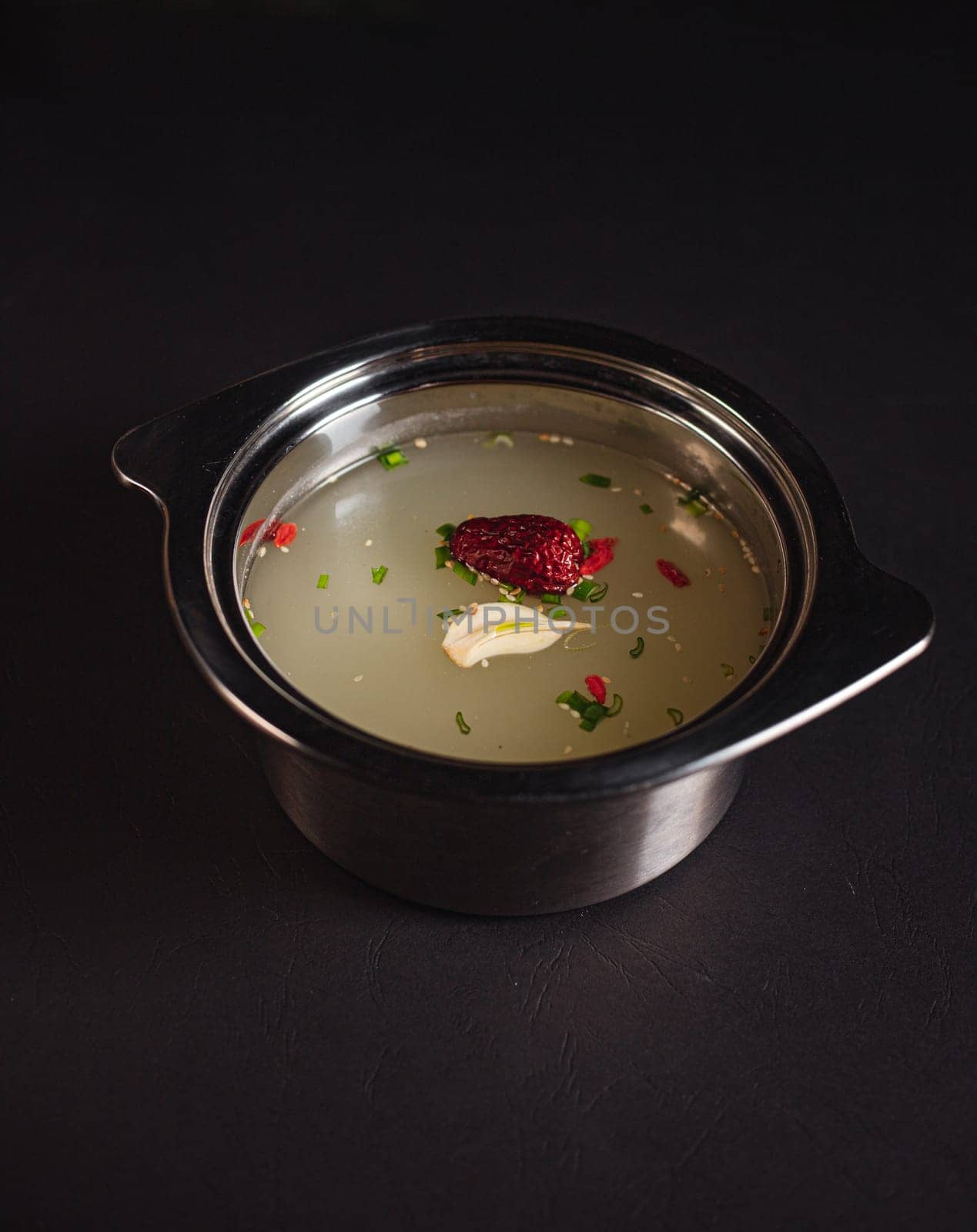 soup broth in an iron plate on a dark background side view by tewolf