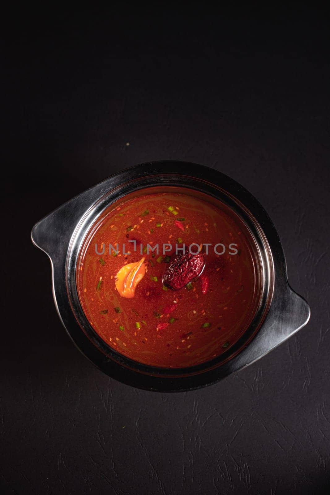 soup broth in an iron plate on a dark background side view by tewolf