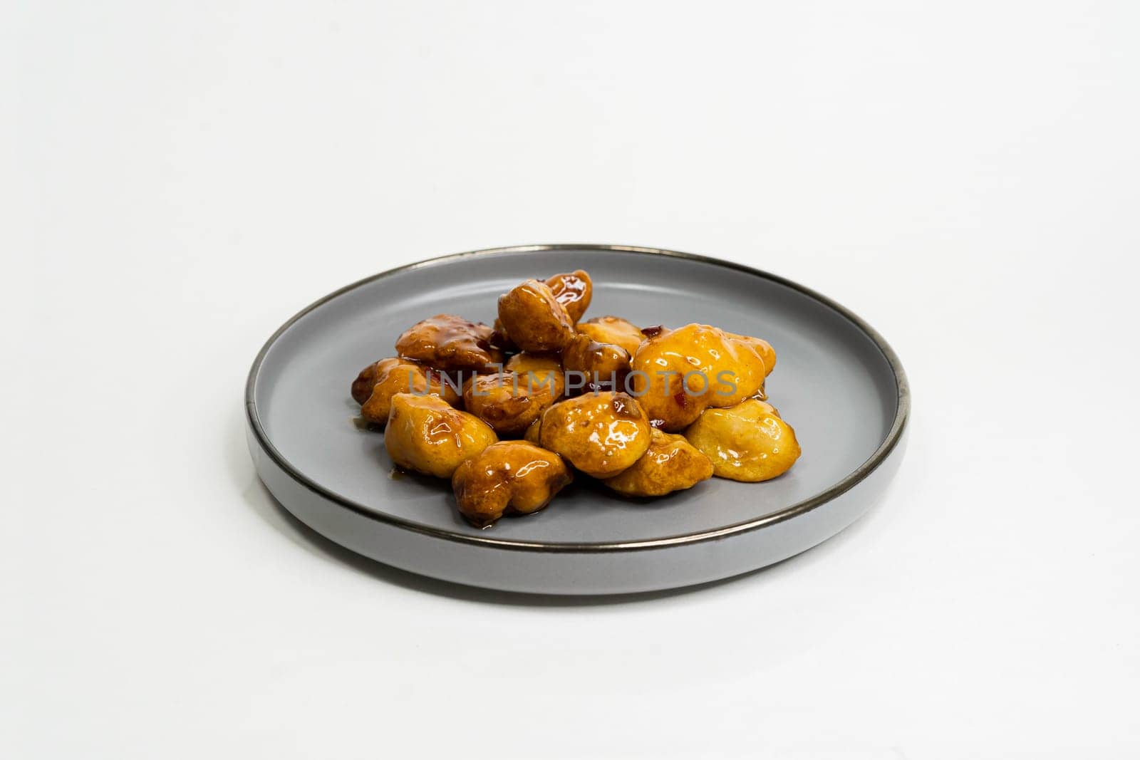 fried chicken nuggets in sauce in a flat plate on a white background side view by tewolf